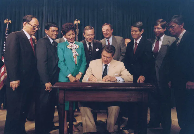 President Ronald Reagan signs the Civil Liberties Act at the White House on 10 August 1988