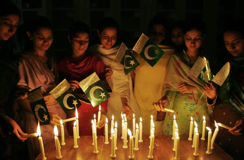 Young Pakistanis light candles and hold the national flag at a midnight celebration of Independence Day