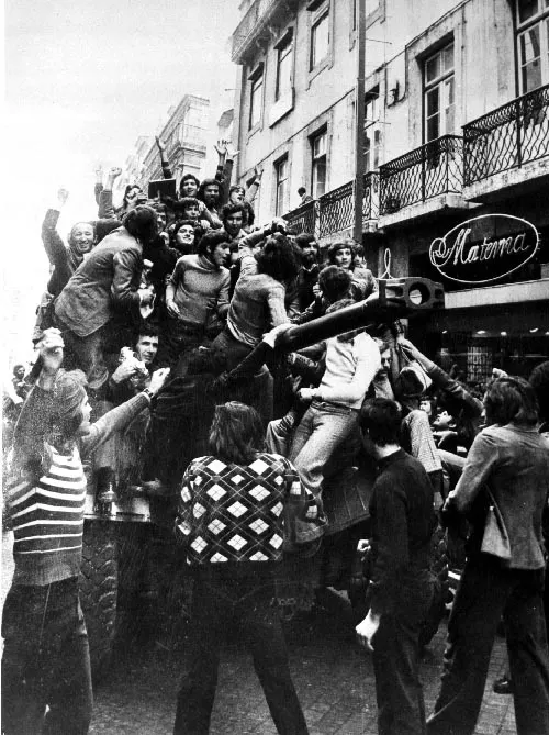 Crowds climb onto a military vehicle in Lisbon during the Carnation Revolution of 1974.