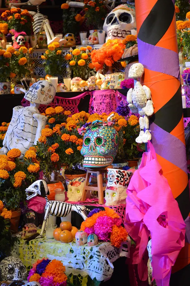 A Day of the Dead altar decorated with marigolds, candles, painted skulls and cut-paper banners.