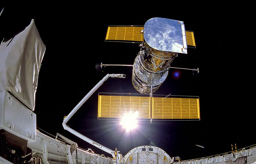 Hubble held on Discovery's robotic arm before its release on 25 April 1990, the day after launch.