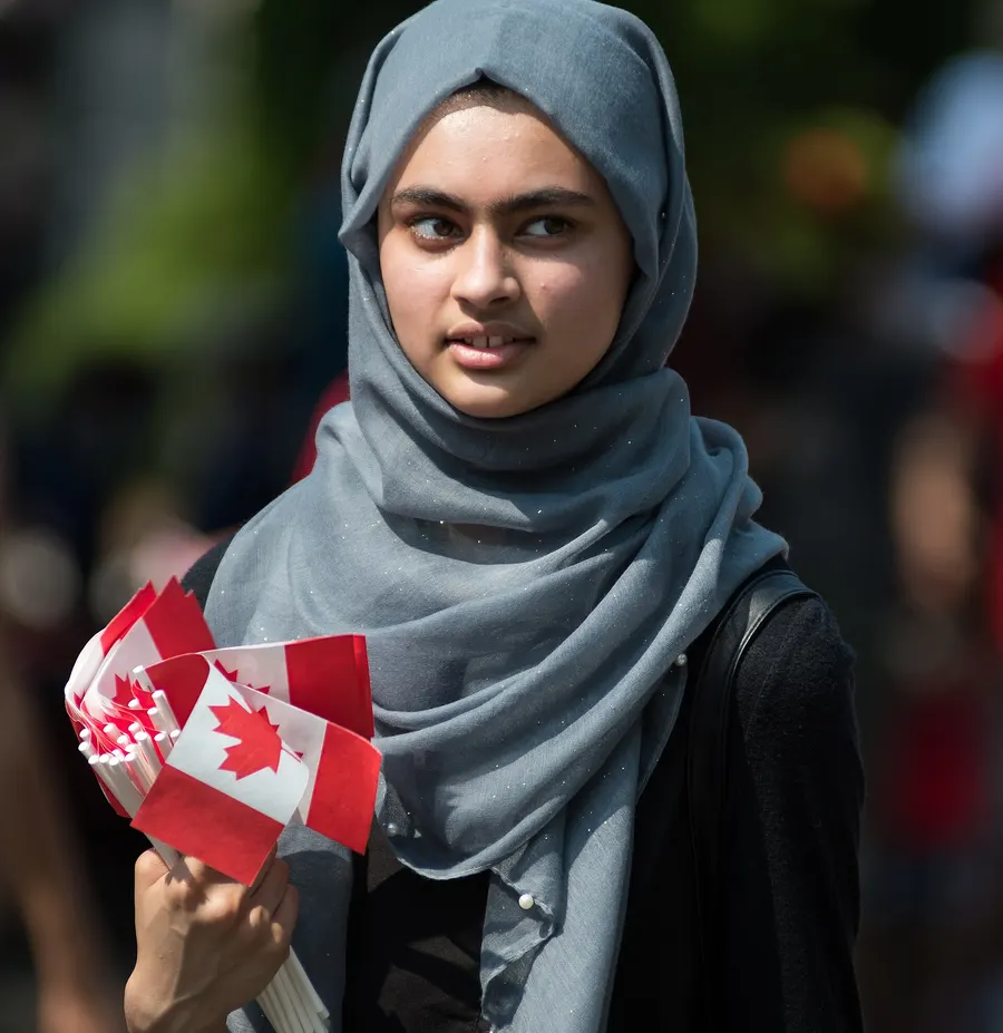 A young woman holding small Canadian flags at Canada Day celebrations in Toronto, 2018