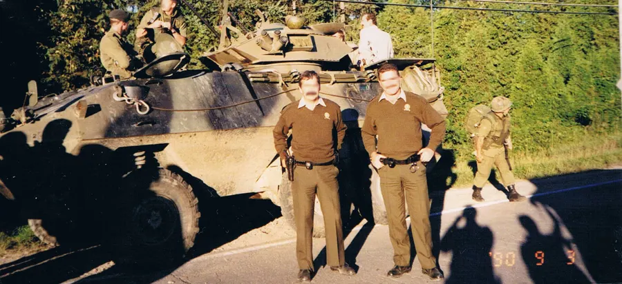 Canadian soldiers and Quebec provincial police beside an armoured vehicle during the Oka Crisis in 1990