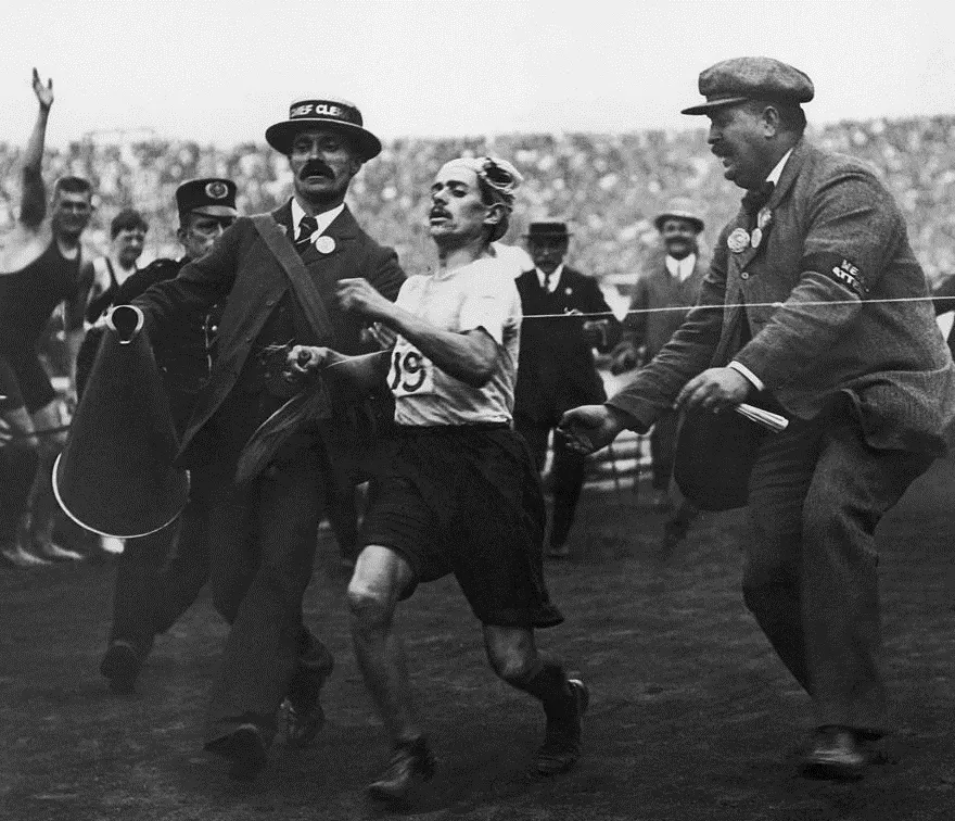 Officials help an exhausted Dorando Pietri towards the finish of the Olympic marathon in London, 1908