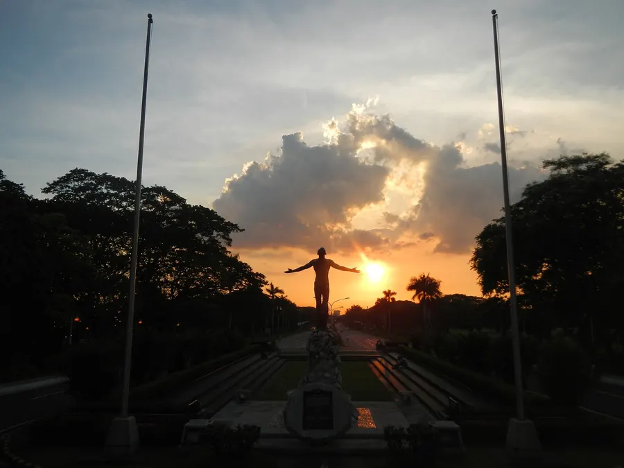The Oblation statue by Guillermo Tolentino at the University of the Philippines, Diliman, seen against the setting sun