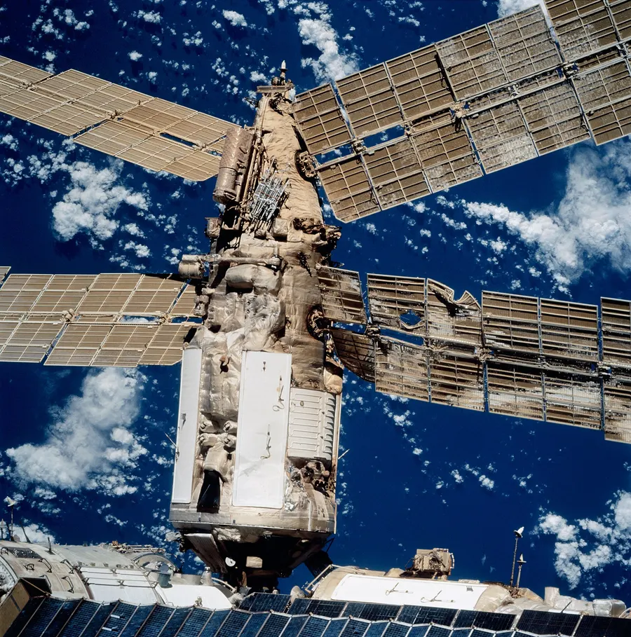 The Mir space station seen from the space shuttle Atlantis in September 1997, with the Spektr module's damaged solar panels