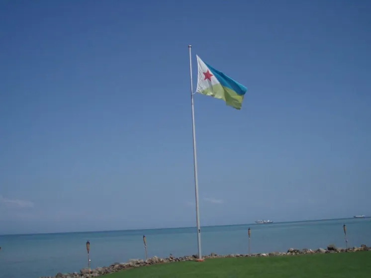 The flag of Djibouti flying beside the sea