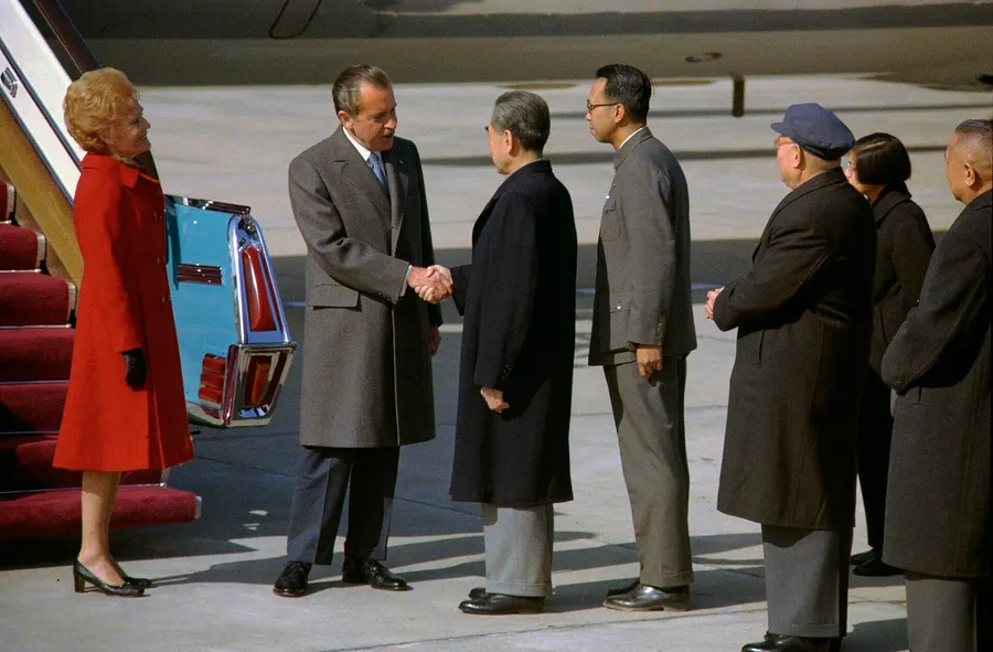 Richard Nixon shakes hands with Premier Zhou Enlai on arrival at Beijing airport, 21 February 1972, with Pat Nixon beside him.