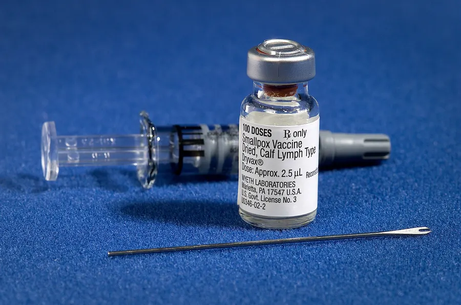 A vial of smallpox vaccine with the bifurcated needle used to give it.