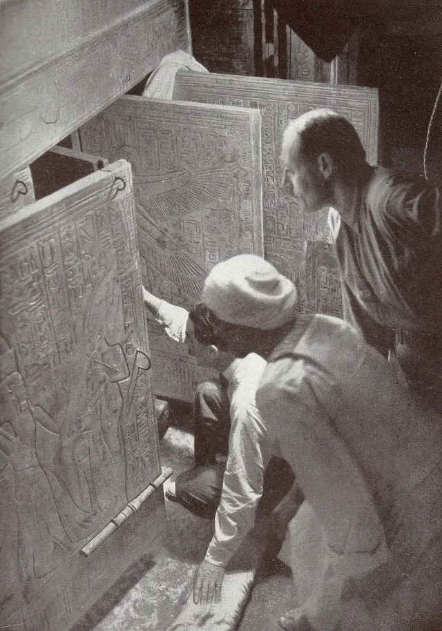 Howard Carter, kneeling, with an Egyptian workman and Arthur Callender at the doors of the burial shrines inside the tomb, January 1924.
