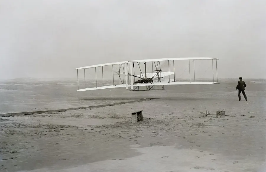 The first flight at Kill Devil Hills, 10.35 a.m.: Orville at the controls, Wilbur running alongside.